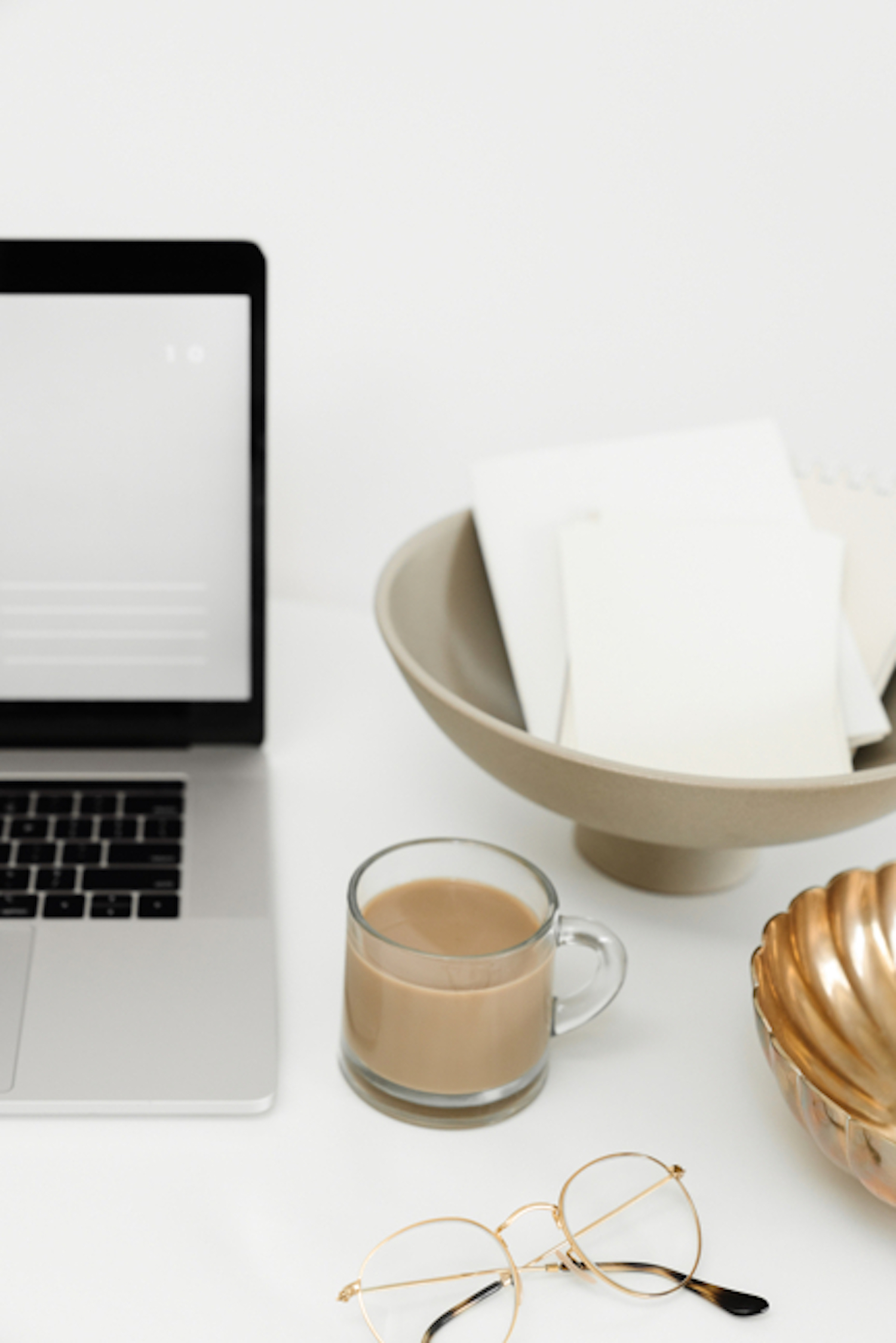 Laptop, coffee and bowl with mail on a desk.