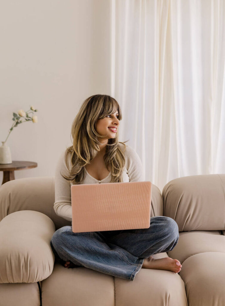 Harj from designed by harj sitting on a couch and working on a laptop